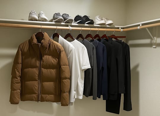 A row of shoes are on a shelf above a row of shoes on the floor.