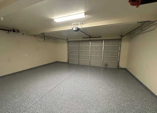 A garage with a closed metal door and a light on the ceiling.