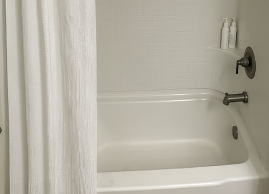 A white bathroom with a white tub and shower curtain.