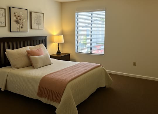 A bedroom with a bed, nightstand, and window.