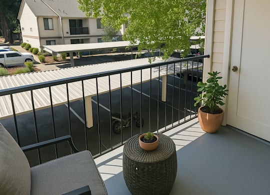 A balcony with a chair, table and potted plant.
