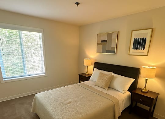 A bedroom with a large bed and two lamps.