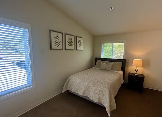 A bedroom with a bed, nightstand, and two wall art pieces.