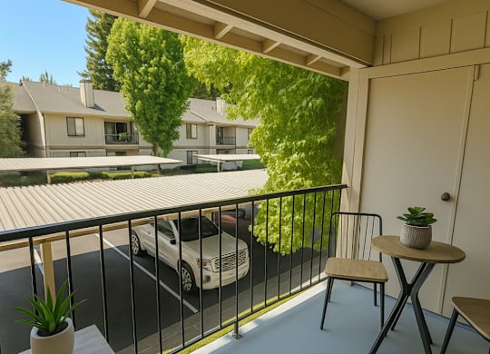 A balcony with a table and chairs overlooking a parking lot.