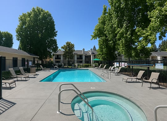 A swimming pool surrounded by chairs and trees.