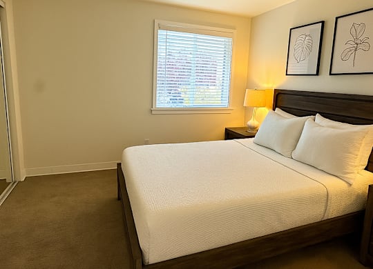 A bedroom with a large bed and two framed pictures on the wall.