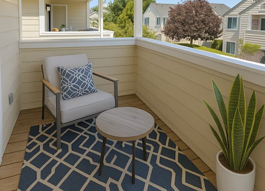 A patio with a chair, table, and potted plant.