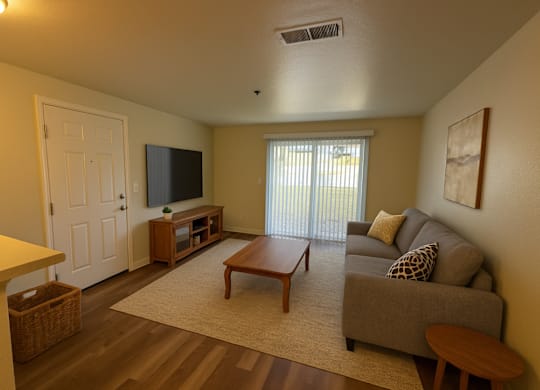A living room with a grey couch, a wooden coffee table, and a flat screen TV.