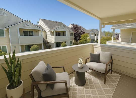 A patio with two chairs and a table with a potted plant on it.