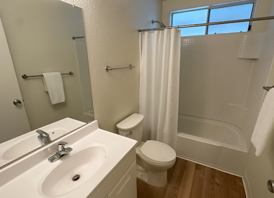 A white bathroom with a toilet, sink, and shower.
