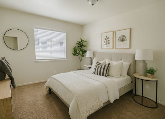 A bedroom with a bed, nightstand, and a plant.