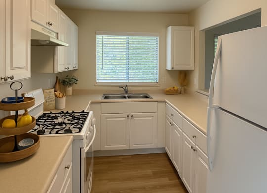 A kitchen with white cabinets and a white refrigerator.