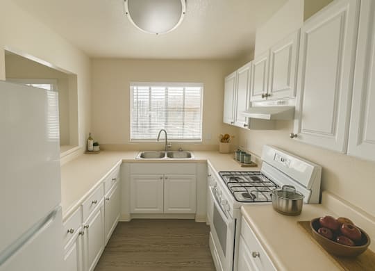 A white kitchen with a sink and a window.