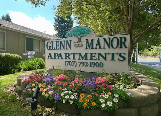 A sign for Glenn Manor Apartments is surrounded by flowers.