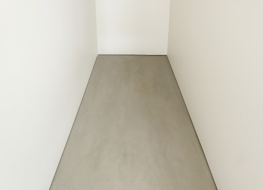 A white hallway with a grey floor.