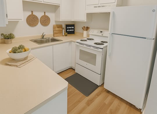 A white kitchen with a sink, stove, and refrigerator.