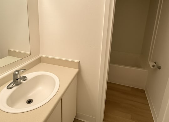 A white bathroom with a sink and mirror.