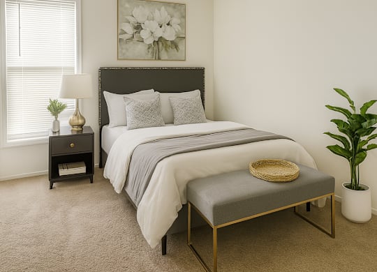 A bedroom with a large bed and a small bench in front of it.
