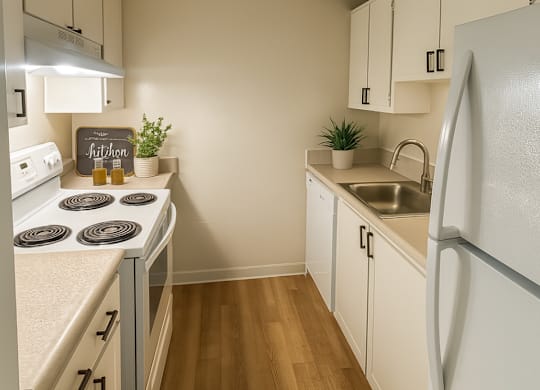 A small kitchen with a white fridge and a white stove.