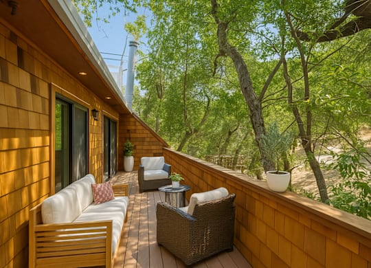 A wooden deck with a white couch and a wicker chair.
