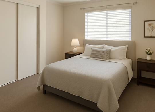 A bedroom with a bed, nightstand, and lamp.
