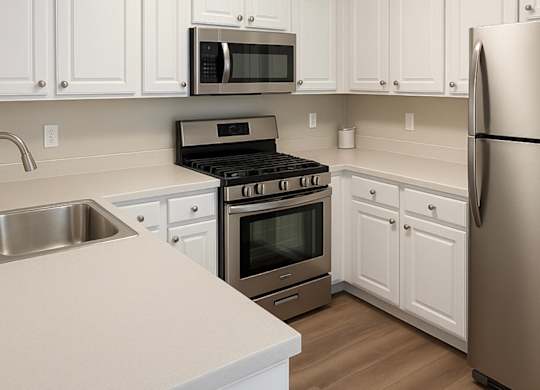 A kitchen with white cabinets and a stainless steel refrigerator.