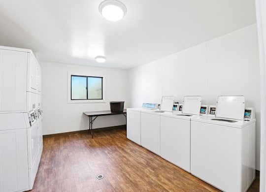 A room with white appliances and a table with a pot on it.