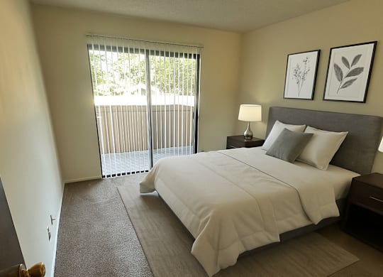 A bedroom with a large bed and a window with blinds.