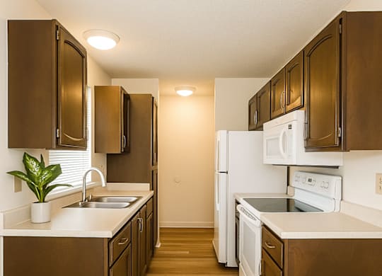 A kitchen with brown cabinets and white appliances.