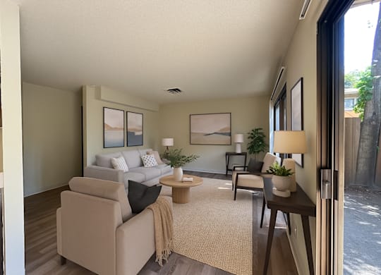 A living room with a couch, a chair, a coffee table, and a potted plant.
