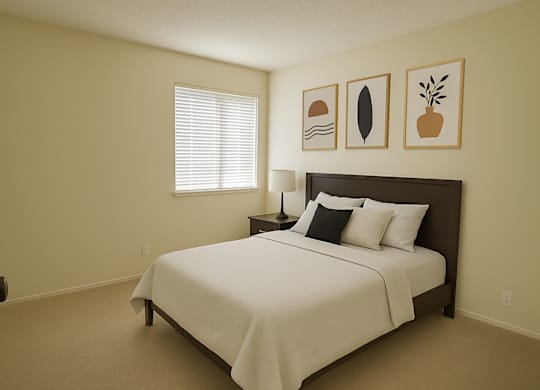 A bedroom with a bed, pillows, and pictures on the wall.