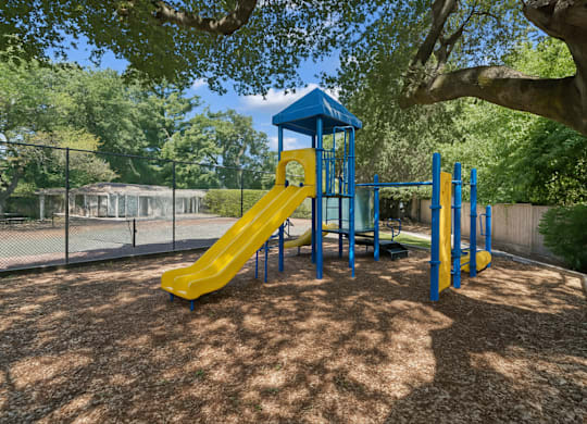A playground with a yellow slide and a blue tower.