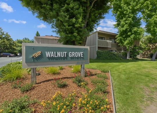 A sign for Walnut Grove stands in front of a building and trees.