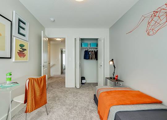 A bedroom with a bed, a chair, and a painting on the wall.