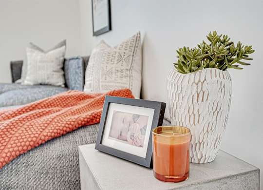 A grey couch with a red throw and a grey pillow with a white design on it.