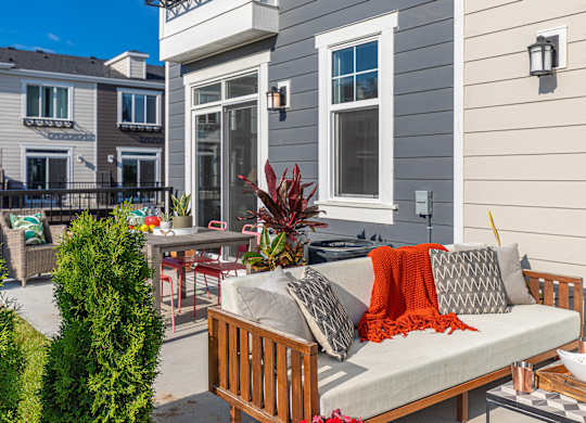 A patio with a couch, chairs, and a table with a bowl of popcorn on it.