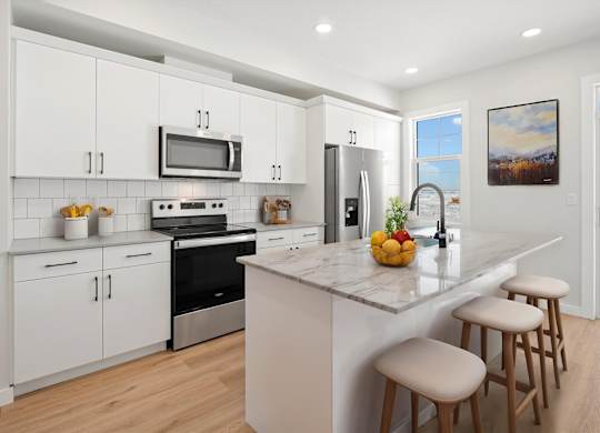 A kitchen with white cabinets and a marble countertop.