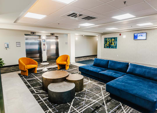 a lobby with blue couches and chairs and tables