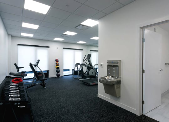 a gym with exercise equipment and a sink in a glass door