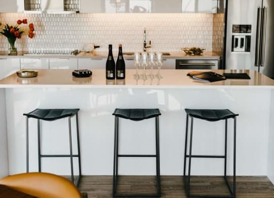 a white kitchen with bar stools and counter tops