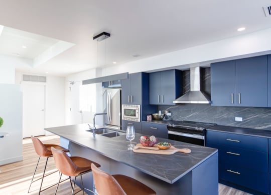 a kitchen with blue cabinets and a marble counter top