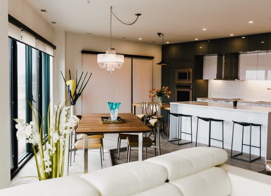 a living room and kitchen with white furniture and a wooden table