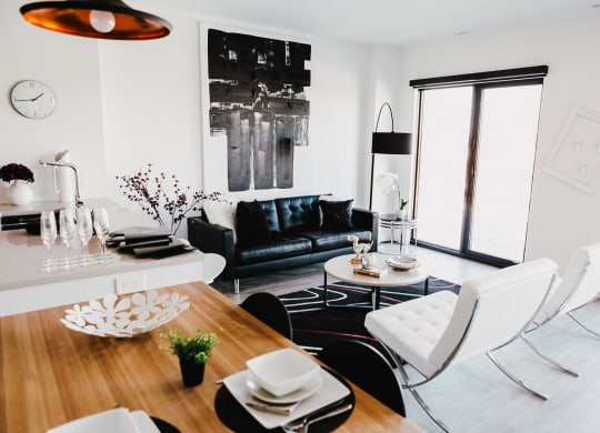 a living room and dining room with white furniture and a black leather couch