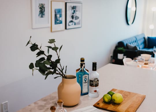 a kitchen counter with a cutting board with fruit and a bottle of wine on it