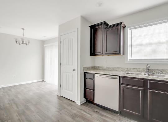 an empty kitchen with dark cabinets and a white door