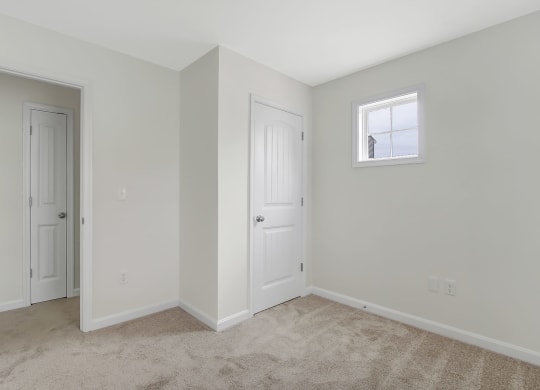 a bedroom with white walls and a door and a window