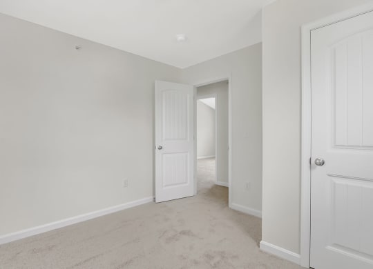 a bedroom with white walls and a door to a hallway