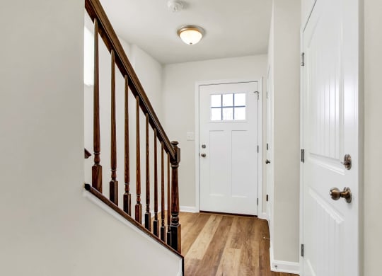 entry foyer with hardwood floors and white door wood rails leading upstairs