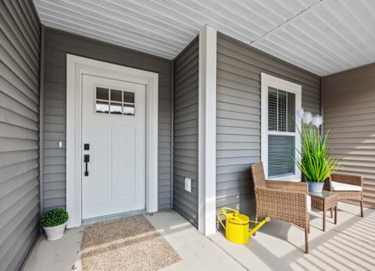 A small porch with a white door and a yellow bucket.