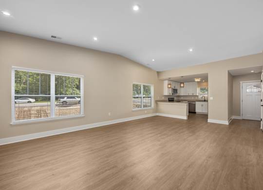A spacious room with wooden flooring and a large window.